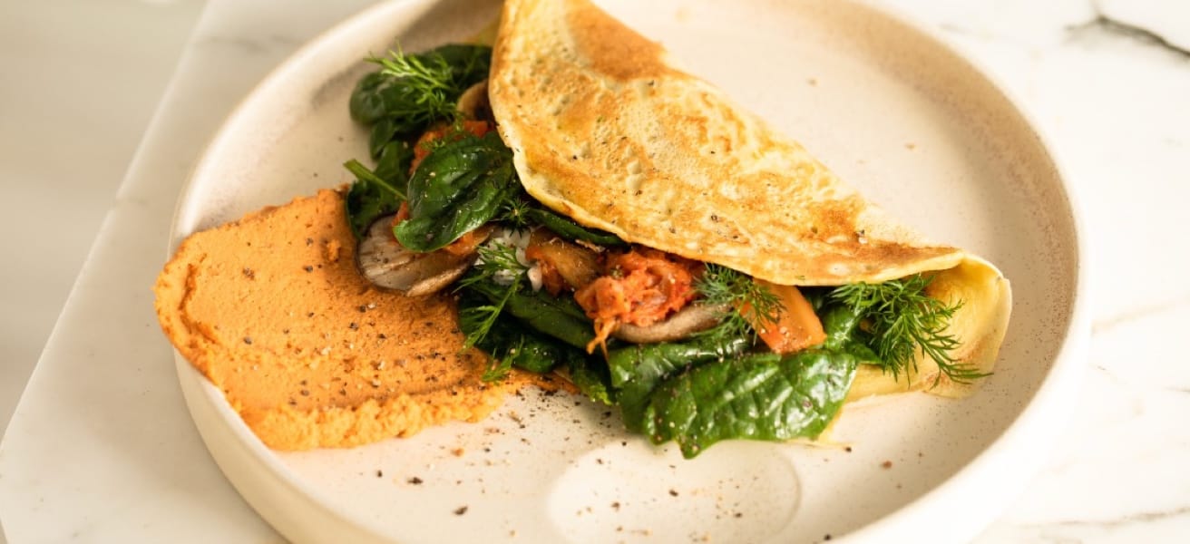 A delicious plate of omlette with vegetables and hummus on the side
